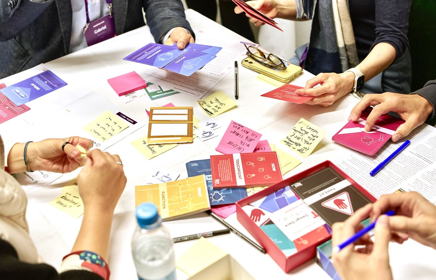 Top-down view of participants collaborating with cards, sticky notes and design materials during a breakout session.