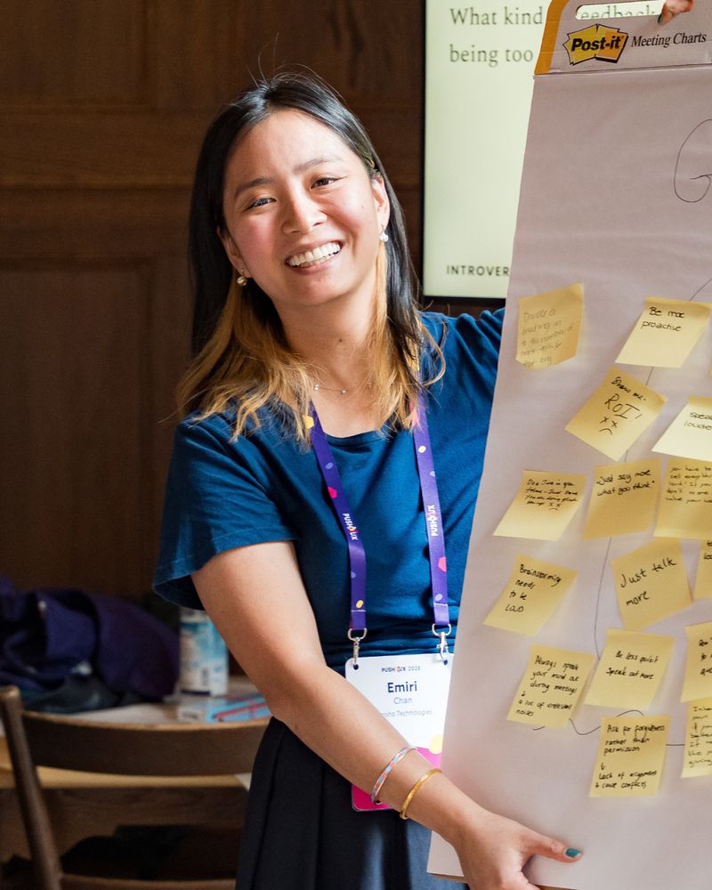 Smiling breakout session host standing next to a flip chart covered in sticky notes from a group exercise.