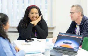 Workshop attendees in conversation around a laptop
