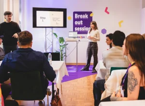 Breakout session room with 2 facilitators in front of a screen, instructing their group.